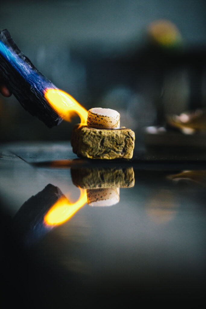 Japanese preparation method of roasting a clam over charcoal wood by the chef of Amsterdam's smallest chef's table restaurant by Chef Filip Hanlo in luxury boutique hotel The Dylan Amsterdam.