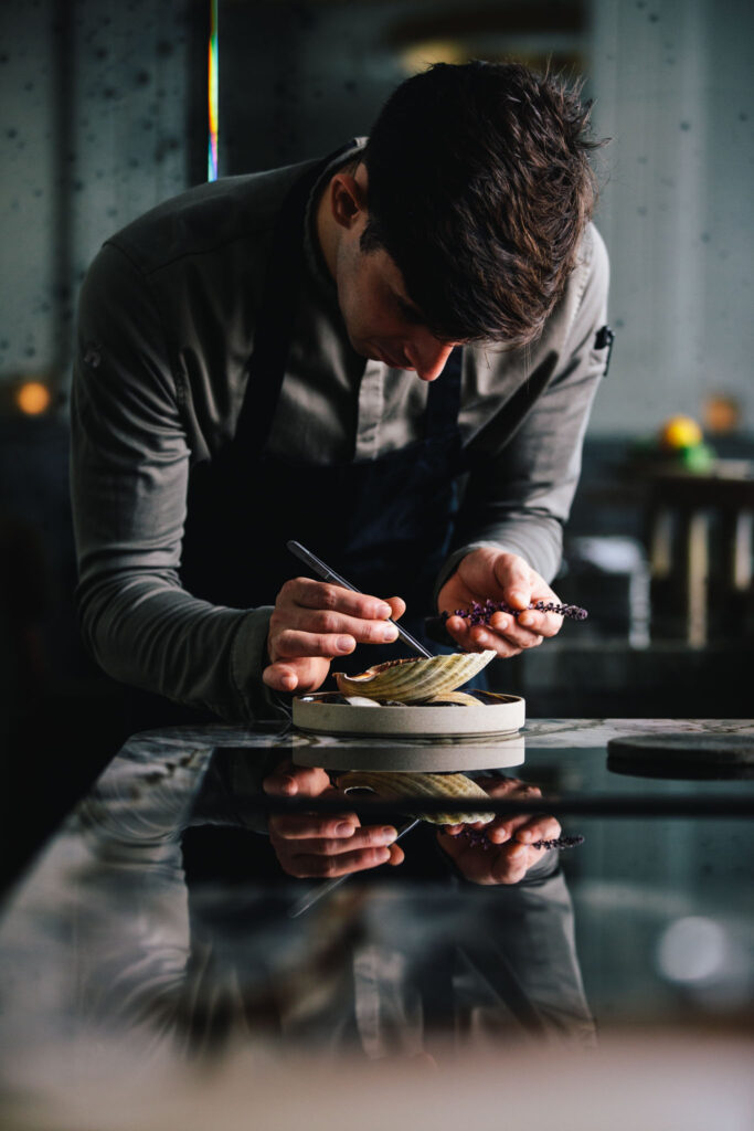 chef Filip Hanlo preparing a clam dish in its shell at chef's table restaurant até amsterdam